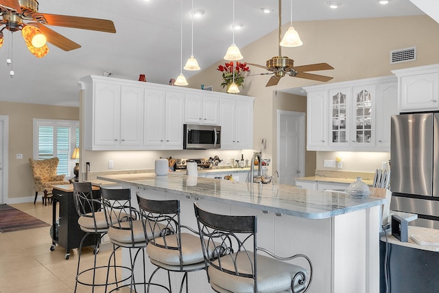 kitchen with appliances with stainless steel finishes, pendant lighting, white cabinets, and light stone countertops