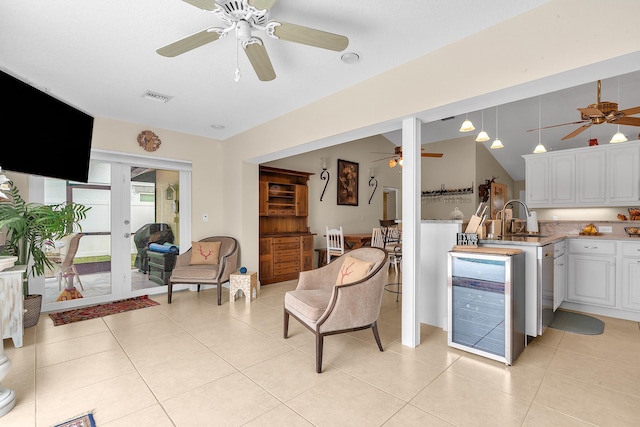 kitchen with light tile patterned floors, wine cooler, hanging light fixtures, white cabinets, and sink