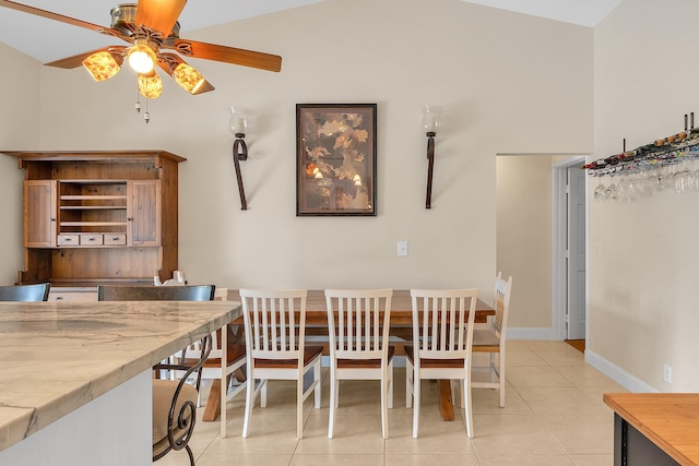 dining area with ceiling fan, light tile patterned floors, and vaulted ceiling