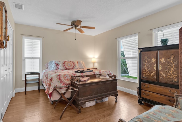 bedroom featuring ceiling fan, wood-type flooring, a closet, and a textured ceiling