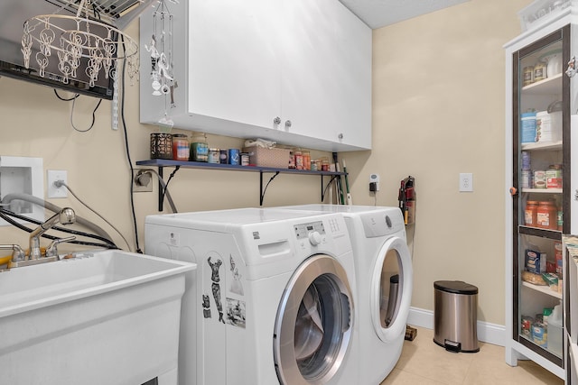 laundry area featuring cabinets, light tile patterned floors, sink, and independent washer and dryer