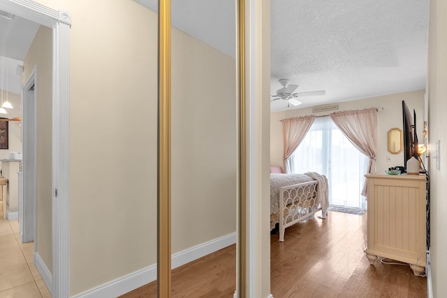 bedroom featuring ceiling fan, light hardwood / wood-style floors, and a textured ceiling