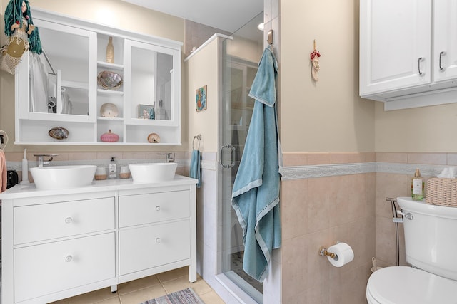 bathroom featuring toilet, tile patterned flooring, tile walls, walk in shower, and vanity