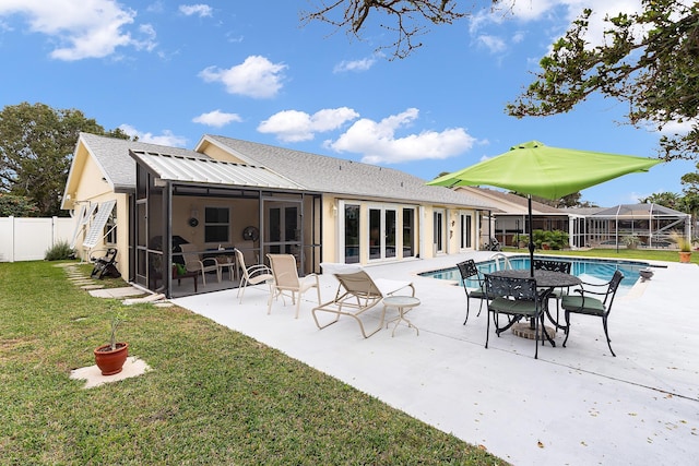 rear view of house featuring a lawn, a patio area, a fenced in pool, and a sunroom