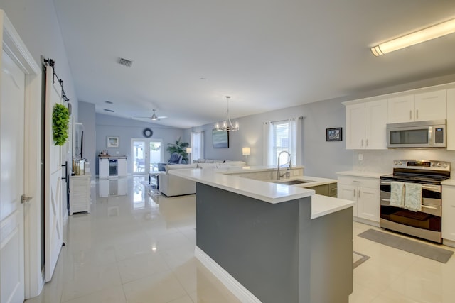 kitchen featuring appliances with stainless steel finishes, sink, white cabinets, hanging light fixtures, and a center island with sink