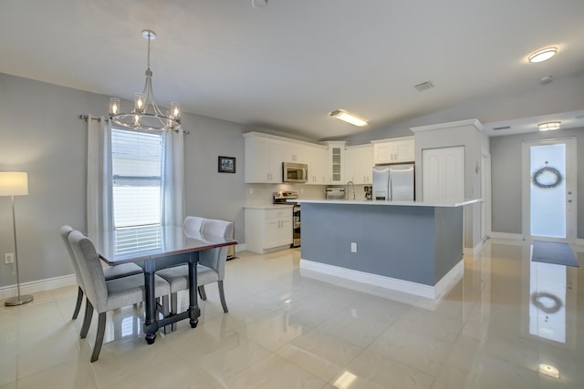 kitchen featuring appliances with stainless steel finishes, white cabinetry, lofted ceiling, hanging light fixtures, and a center island