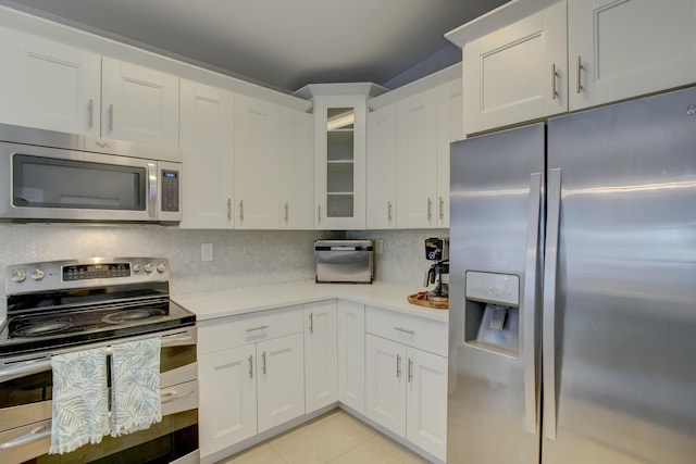 kitchen with tasteful backsplash, white cabinetry, appliances with stainless steel finishes, and light tile patterned floors