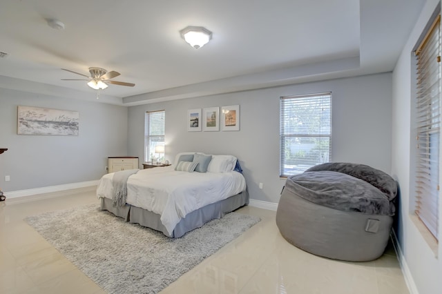 bedroom with multiple windows, a tray ceiling, and ceiling fan