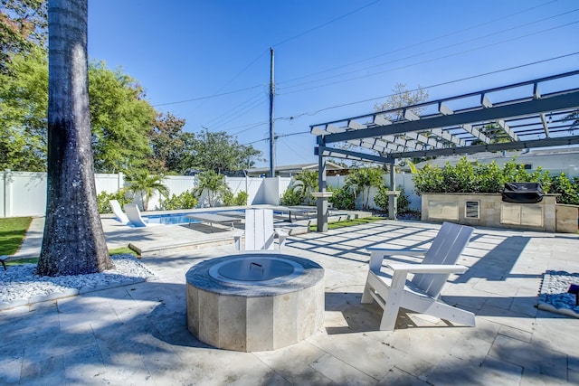 view of patio featuring a fenced in pool, a fire pit, a pergola, grilling area, and exterior kitchen