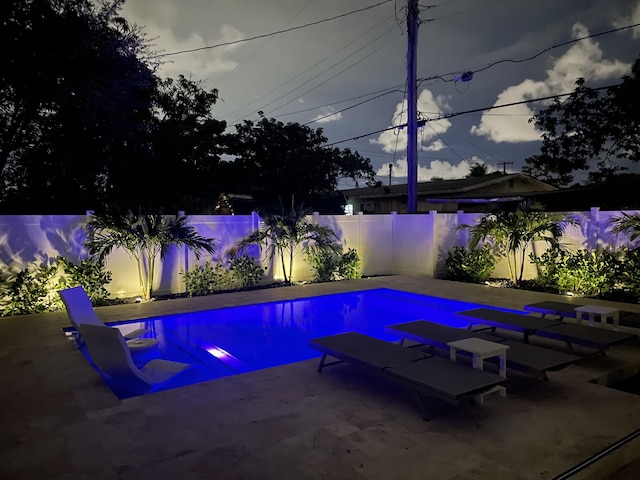 pool at dusk with a patio area