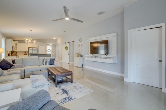 living room with a barn door and ceiling fan with notable chandelier