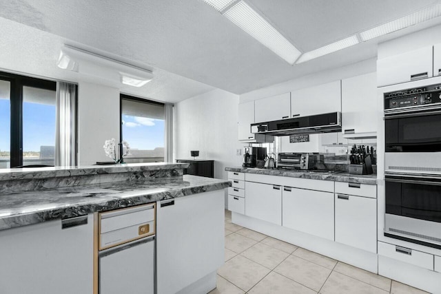 100 Lakeshore Dr Unit 252, North Palm Beach, FL 33408 - kitchen with white cabinets, light tile patterned floors, extractor fan, and double oven