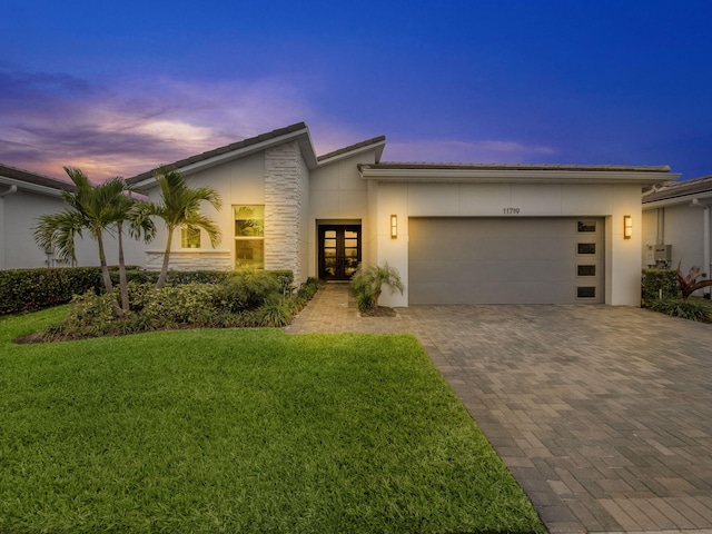 contemporary home featuring a garage, a yard, and french doors