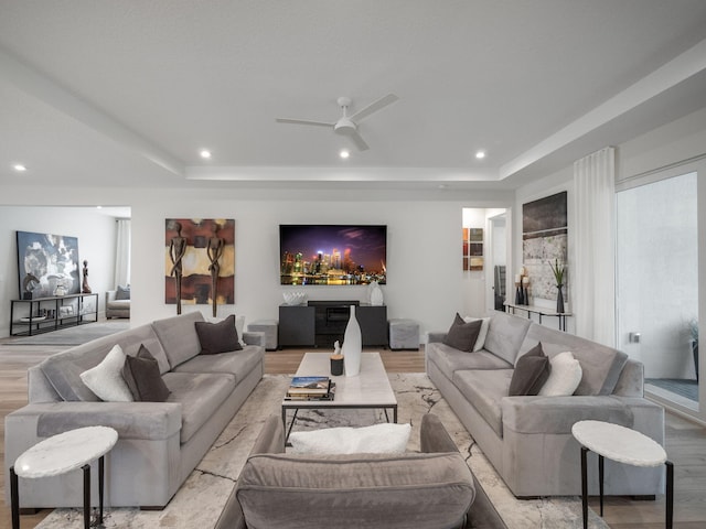 living room featuring a tray ceiling, light hardwood / wood-style flooring, and ceiling fan