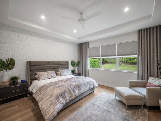 bedroom featuring ceiling fan, a raised ceiling, and hardwood / wood-style floors