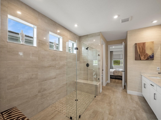 bathroom featuring plenty of natural light, vanity, and a tile shower