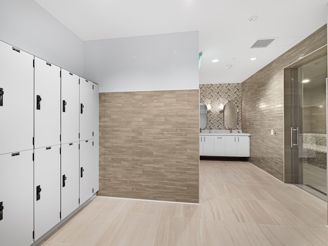 interior space featuring tile patterned flooring, vanity, tile walls, and an enclosed shower