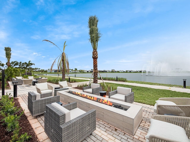 view of patio with a water view and an outdoor living space with a fire pit