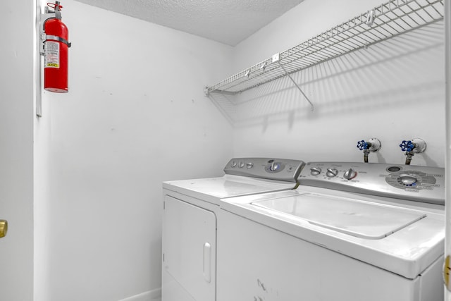 clothes washing area with a textured ceiling and independent washer and dryer