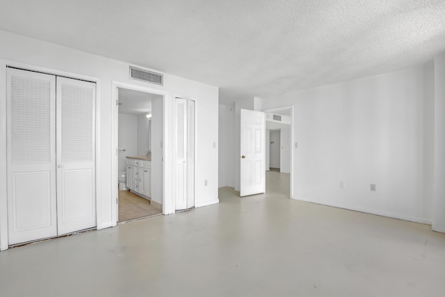 unfurnished bedroom featuring a textured ceiling and ensuite bath