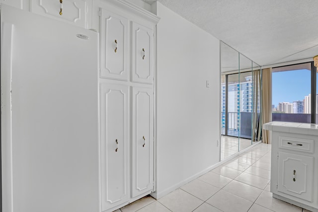 corridor featuring a textured ceiling, light tile patterned flooring, and a wall of windows