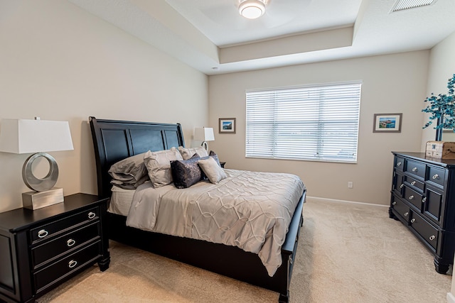 bedroom with light carpet and a tray ceiling