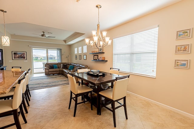 dining room featuring a raised ceiling, light tile patterned floors, and ceiling fan