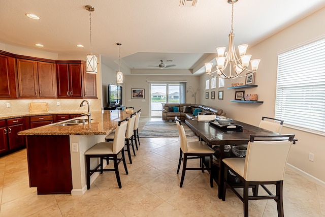 dining room featuring ceiling fan, a raised ceiling, sink, and light tile patterned floors