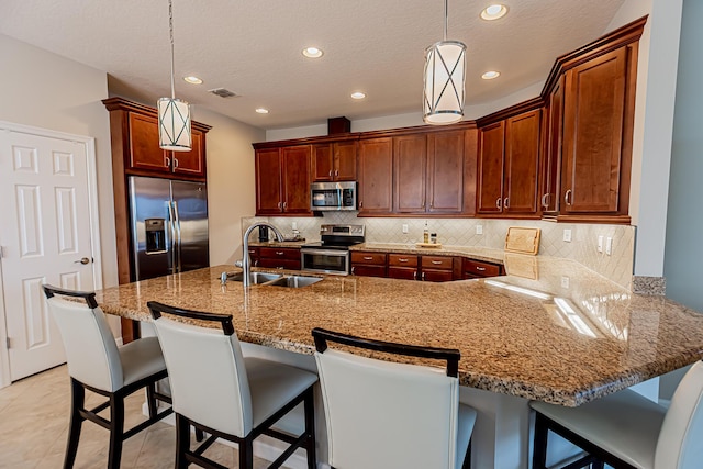 kitchen with sink, decorative light fixtures, stainless steel appliances, and a breakfast bar