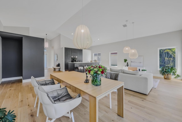 dining space featuring light wood-type flooring and high vaulted ceiling