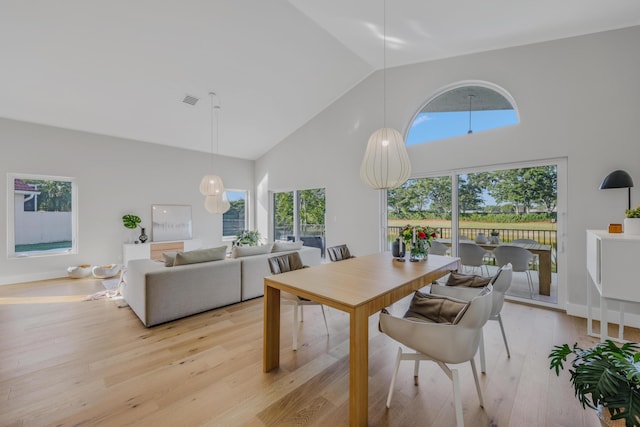 dining room featuring high vaulted ceiling and light hardwood / wood-style floors