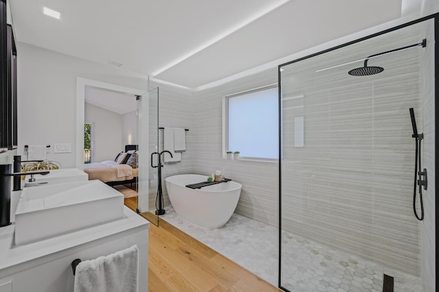 bathroom with shower with separate bathtub, tile walls, lofted ceiling, wood-type flooring, and vanity