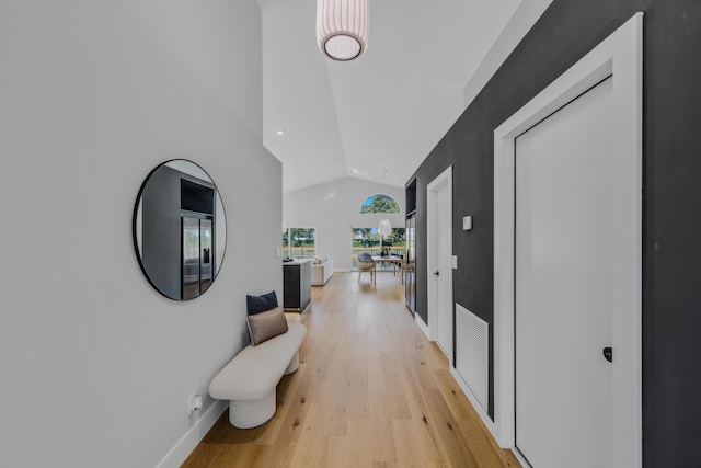 hallway with light wood-type flooring and vaulted ceiling