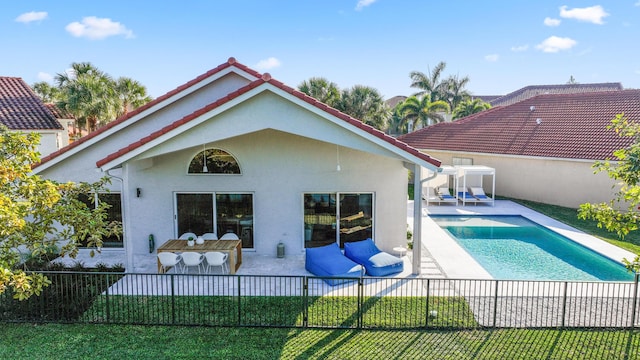 rear view of house featuring a patio, a fenced in pool, and a yard