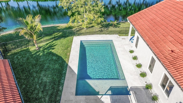 view of swimming pool featuring a patio, a water view, and a yard