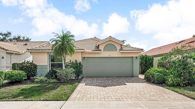 9779 Harbour Lake Cir, Boynton Beach, FL 33437 - view of front of house featuring decorative driveway, a tiled roof, an attached garage, stucco siding, and brick siding