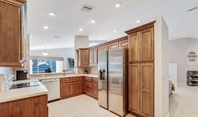 kitchen with light tile patterned flooring, white appliances, hanging light fixtures, and vaulted ceiling