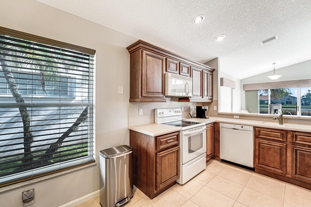 kitchen featuring light tile patterned floors, plenty of natural light, white appliances, vaulted ceiling, and sink