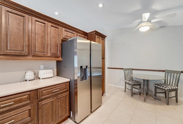 kitchen with ceiling fan, light tile patterned floors, stainless steel refrigerator with ice dispenser, and a textured ceiling