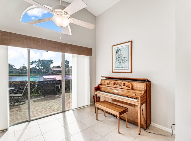 misc room with ceiling fan, light tile patterned floors, lofted ceiling, and a water view