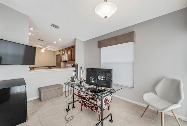 office area with a textured ceiling, ceiling fan, and light tile patterned floors