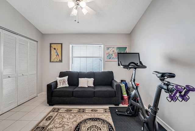 workout area with ceiling fan, a textured ceiling, and light tile patterned flooring