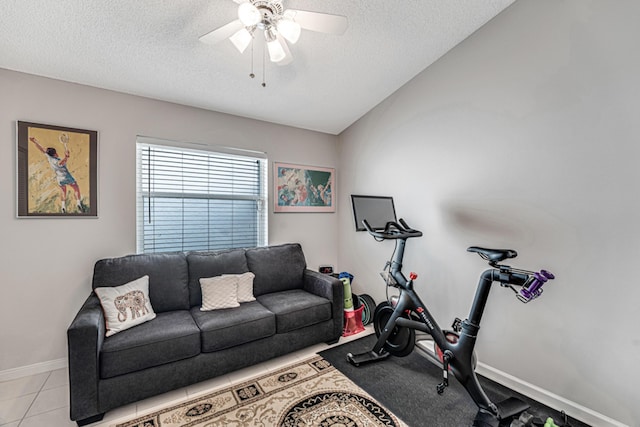 exercise area with ceiling fan, a textured ceiling, and light tile patterned flooring