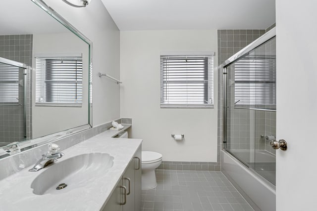 full bathroom featuring toilet, vanity, tile patterned flooring, and enclosed tub / shower combo