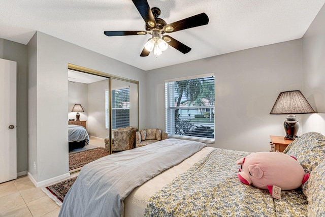 bedroom with a textured ceiling, ceiling fan, light tile patterned floors, and a closet