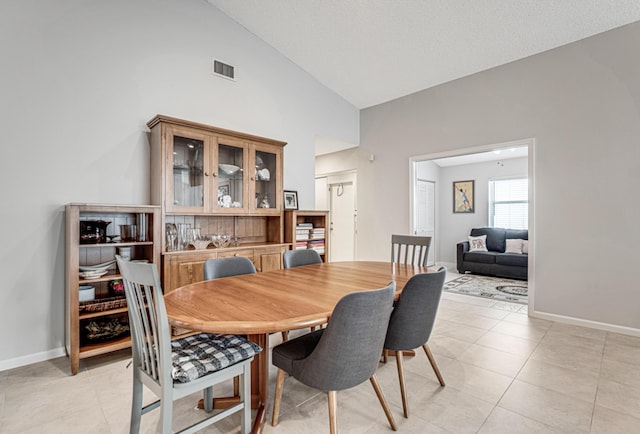 tiled dining space featuring high vaulted ceiling