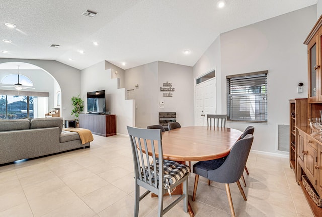 tiled dining room with ceiling fan, plenty of natural light, a textured ceiling, and vaulted ceiling