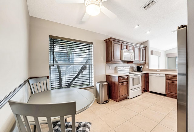 kitchen with white appliances, a textured ceiling, lofted ceiling, ceiling fan, and light tile patterned floors