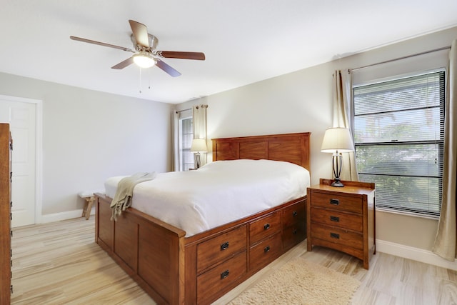 bedroom with multiple windows, light hardwood / wood-style floors, and ceiling fan