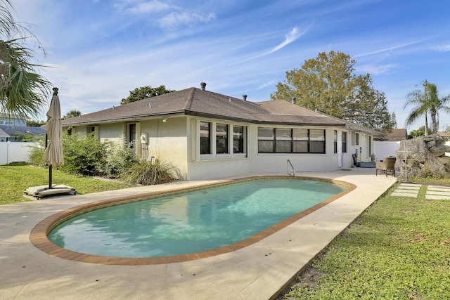 rear view of house with a fenced in pool and a patio